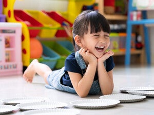 Niña acostada en un cuarto de juegos, riendo. Concepto de comportamiento, emociones y desarrollo emocional en niños.