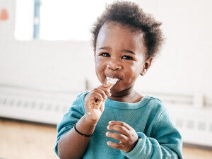 Niño pequeño sonriendo y comiendo con una cuchara