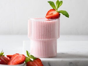 Un vaso contiene batido de fresa y la fruta de decoración