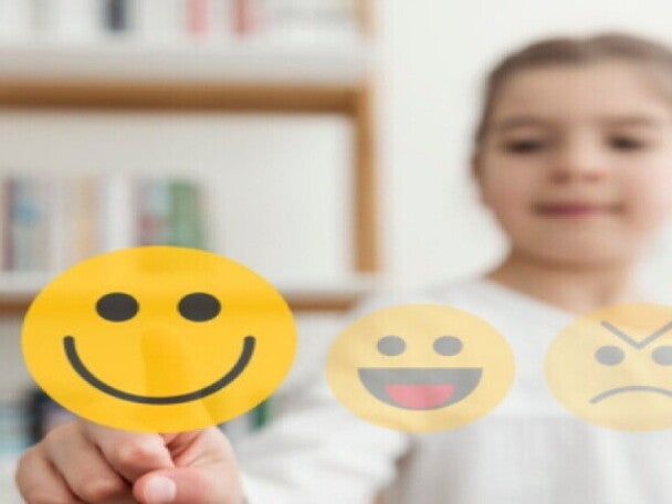 Niña seleccionando el estado de animo mediante emoticones imaginarios