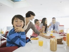 Familia el desayuno juntos en la cocina, sentados alrededor de la mesa.