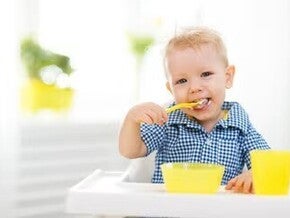Niño rubio comiendo alegre un menú infantil