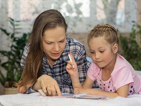 Conoce los diferentes estilos de aprendizaje. Mamá explicando a su hija por medio de un libro.