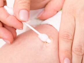 Mamá limpia el ombligo del bebé recién nacido con un hisopo de algodón