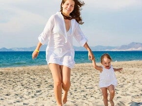 mamá bebé caminado felices Mamá con bebe caminando y jugando en la playa cuidan de su salud