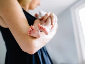 Cómo aliviar cólicos en bebés Mamá meciendo a bebé recién nacido.