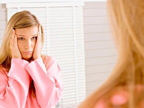 Mujer preocupada al mirarse en el espejo por dificultades para embarazarse