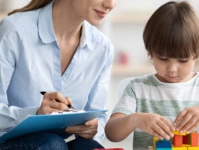Profesora mirando a un niño que esta armando con bloques