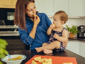 Identifica cuáles son las frutas ideales para iniciar esta nueva etapa de tu bebé Mamá y bebé comiendo fruta en la cocina