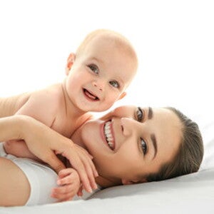 Bebé y mamá sonrientes sobre una cama Bebé y mamá sonrientes sobre una cama