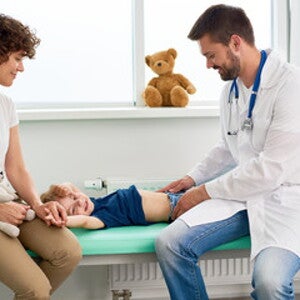 Doctor examinando con sus manos estómago de niño Doctor examinando con sus manos estómago de niño