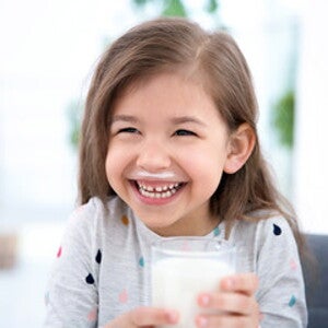 Niña sonriente tomando un vaso con leche Niña sonriente tomando un vaso con leche