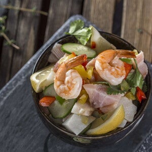 Ceviche Tropical con Palmitos de cangrejo Un bowl con ceviche tropical y un limon al costado