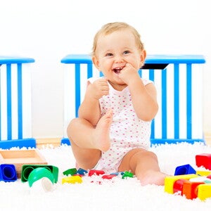 Es importante saber a los cuántos meses se sienta un bebé y acompañar este proceso Bebé sonriendo sentado al lado de sus juguetes