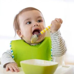 Los beneficios de usar baberos para bebés en la alimentación Bebé alimentándose con un babero puesto.