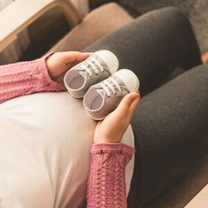 Conoce qué es el bebé arcoíris. Mamá embarazada de un bebé arcoíris cogiendo unos zapatitos.
