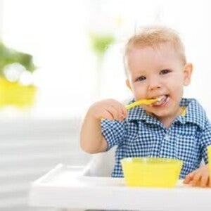 Niño rubio comiendo alegre un menú infantil
