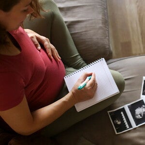 Tener un embarazo múltiple es muy común. Mamá con un cuaderno mirando la ecografía de su embarazo múltiple.