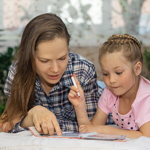 Conoce los diferentes estilos de aprendizaje. Mamá explicando a su hija por medio de un libro.
