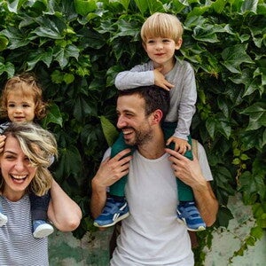 Estilos de crianza para educar a mi hijo. Los padres riendo con los hijos alzados.