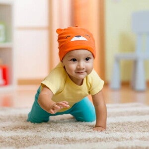 Bebé de 7 meses gateando sobre alfombra.