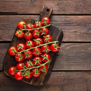 Huevo a las hierbas con tomate cherry y guatila tomates cherry sobre una tabla de picar