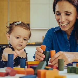 Bebé y mamá jugando con bloques La mamá y la bebé compartiendo con los bloques