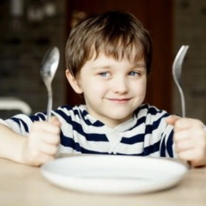 Niño alegre con sus cubiertos esperando comer alimentos constructores Niño alegre con sus cubiertos esperando comer alimentos constructores