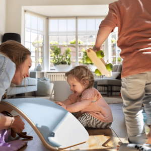 Tiempo de calidad con sobrinos Mujer adulta y dos niños juegan en una sala, con un tablero de equilibrio y un coche de juguete.
