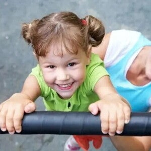 Niña sonriendo jugando en el pasamanos.