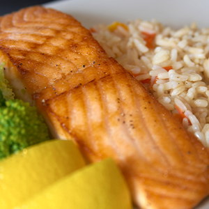 Omega-3 y el rendimiento escolar Plato con salmón a la parrilla, arroz con verduras, brócoli y rodajas de limón