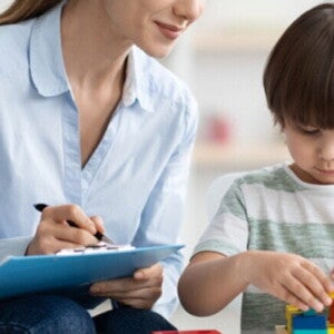 Desarrollo infantil desde los 3 años Profesora mirando a un niño que esta armando con bloques