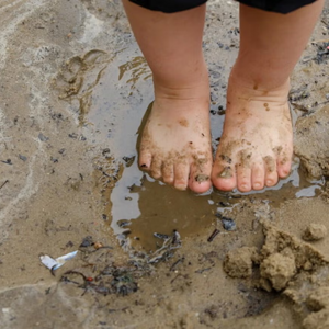 Pies de niño pequeño sobre agua con lodo aprende ensuciándose.