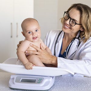 La tabla de peso en niños es un herramienta muy útil. Doctora pesando al bebé.