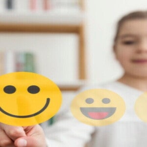Tipos de emociones: Cómo enseñar a los niños a manejarlas Niña seleccionando el estado de animo mediante emoticones imaginarios