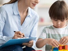 Profesora mirando a un niño que esta armando con bloques