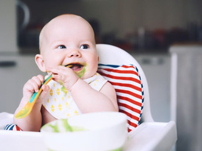 Bebé alegre comiendo con cuchara Bebé alegre comiendo con cuchara