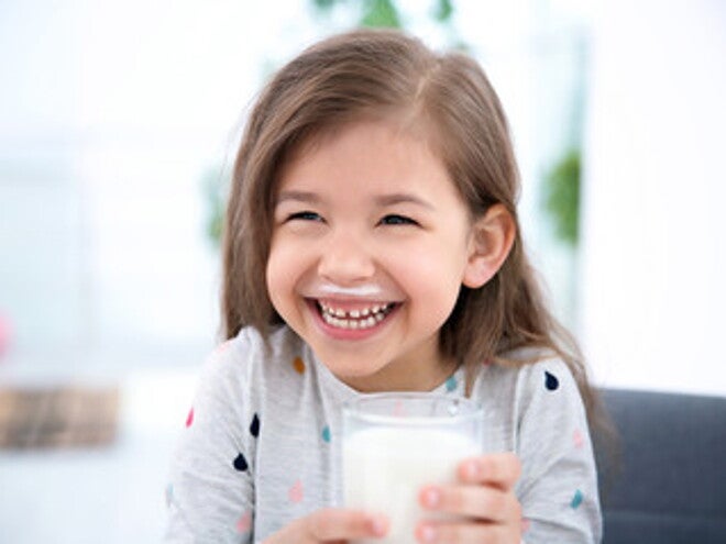 Niña sonriente tomando un vaso con leche Niña sonriente tomando un vaso con leche