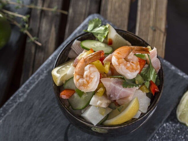 Ceviche Tropical con Palmitos de cangrejo Un bowl con ceviche tropical y un limon al costado