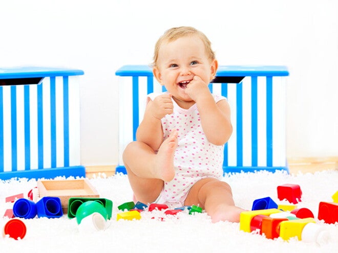 Es importante saber a los cuántos meses se sienta un bebé y acompañar este proceso Bebé sonriendo sentado al lado de sus juguetes
