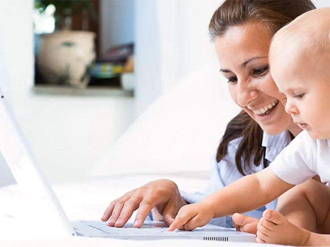 ¿Es posible conciliar la lactancia con el trabajo? Mamá y bebé sonreindo en frente de un ordenador portátil