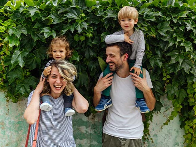 Estilos de crianza para educar a mi hijo. Los padres riendo con los hijos alzados.
