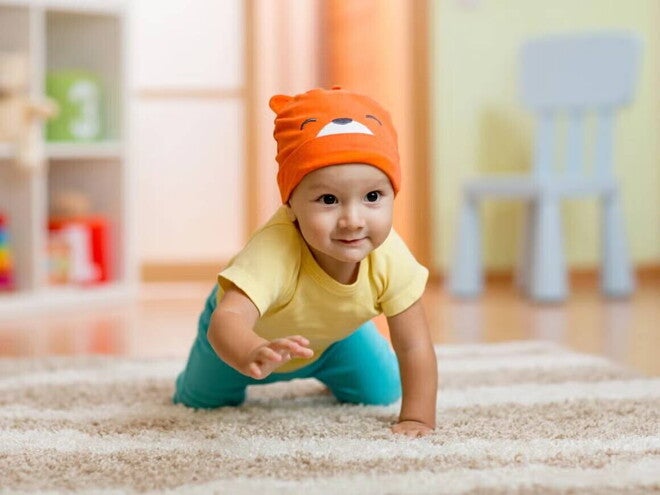 Bebé de 7 meses gateando sobre alfombra.