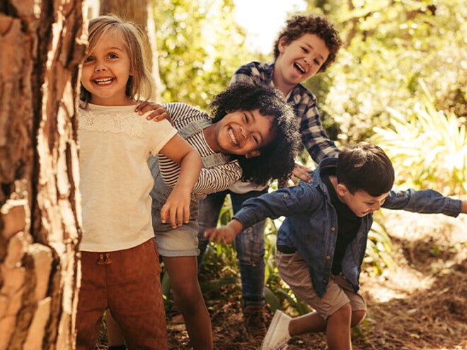 Conoce la importancia de gestionar las emociones en los niños. Niños sonriendo en un parque.