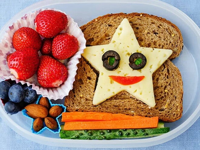 Ideas de loncheras escolares saludables Lonchera escolar saludable y creativa, tostada con queso en forma de estrella, carita feliz y fruta.