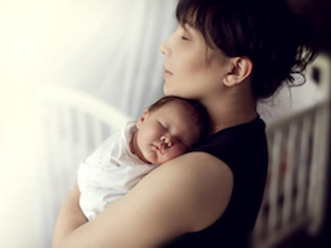 Cuidados para evitar complicaciones del puerperio Mamá abrazando a bebé durmiendo en el periodo del puerperio.