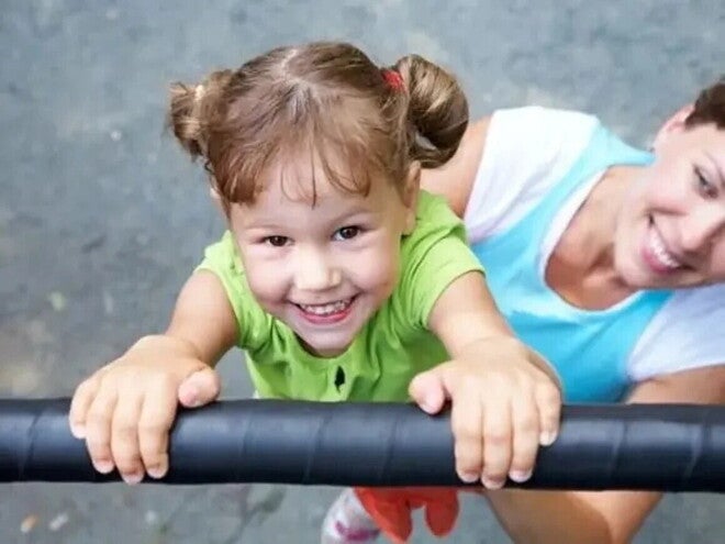 Niña sonriendo jugando en el pasamanos.