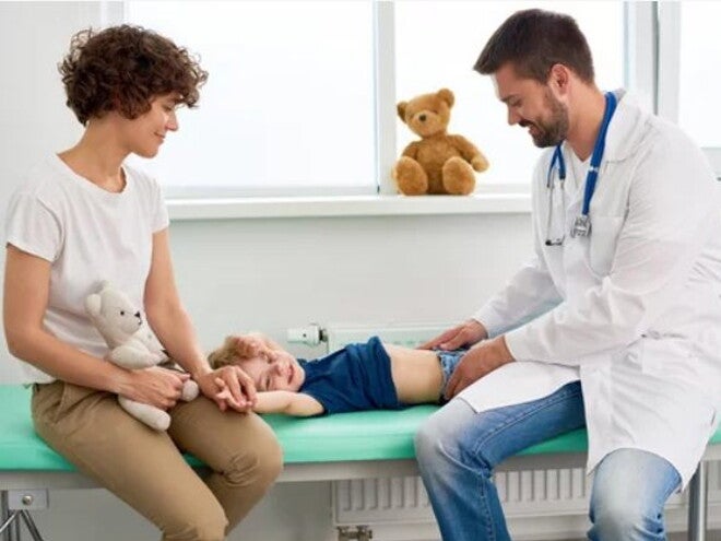 Doctor examinando con sus manos estómago de niño Doctor examinando con sus manos estómago de niño