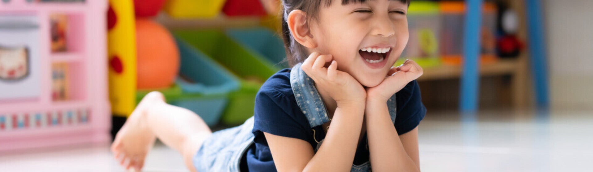 Niña acostada en un cuarto de juegos, riendo. Concepto de comportamiento, emociones y desarrollo emocional en niños.
