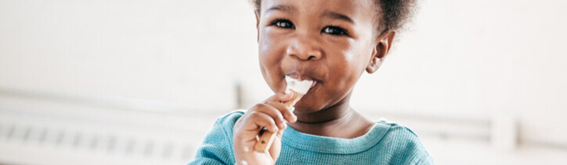 Niño pequeño sonriendo y comiendo con una cuchara